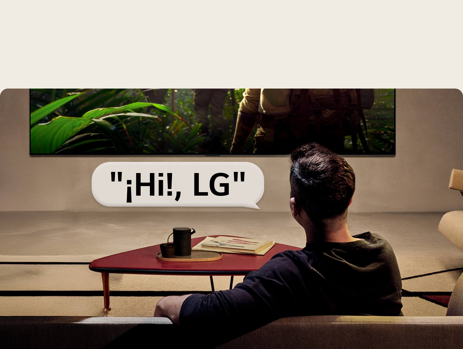 El LG OLED evo AI G6 con Reconocimiento de Voz de campo lejano se activa a través de un comando de voz cuando una persona sentada en una habitación dice "¡Hi!, LG" hacia el televisor, lo que indica una interacción de voz de manos libres dentro de la interfaz del televisor.